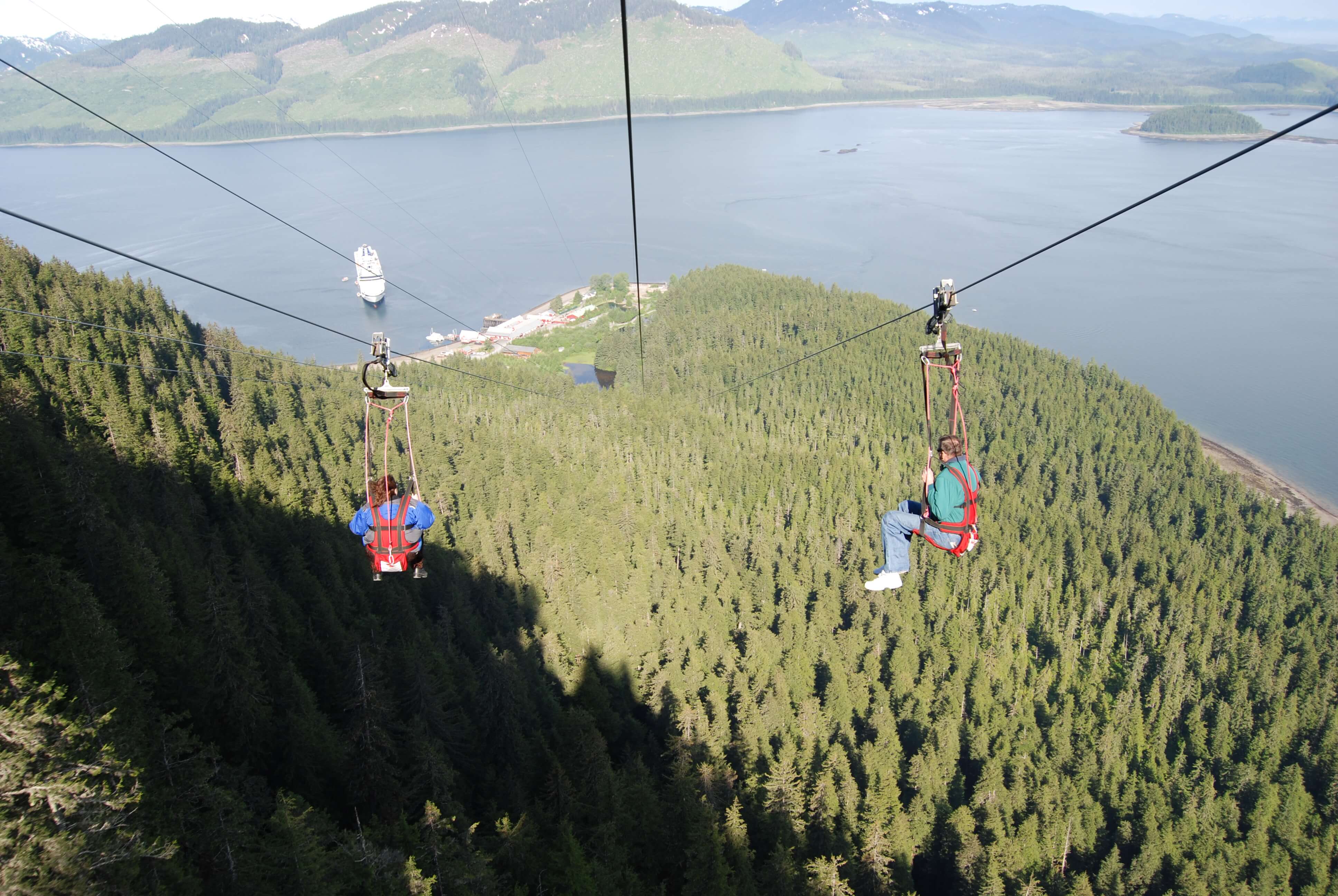 two or 2 people going down zip line or ziplines with view of ocean, Hoonah, Alaska, shore excursion, Icy Strait Point or Pt. PLEASE INCLUDE THE FOLLOWING COPY WHENEVER THIS IMAGE IS USED - Used with permission of Icy Strait Point and Huna Totem Corporation